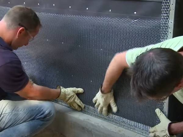 Two workers are laying the metal lath in place.